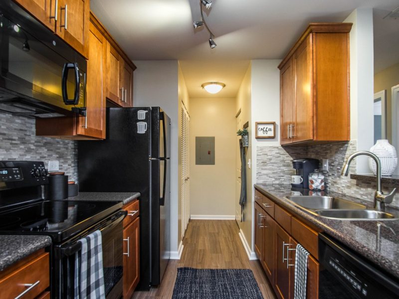 This image shows an expansive view of the Premium Apartment Feature, especially the kitchen island showcasing a neat granite-inspired countertop, accessible kitchen pieces of equipment, and an aisle directly through the dining area.